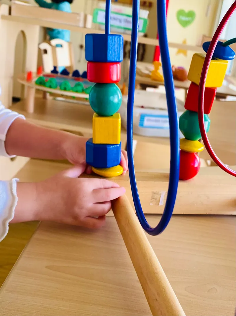 Kinderhände greifen nach bunten Holzperlen – Förderung von Fein- und Graphomotorik