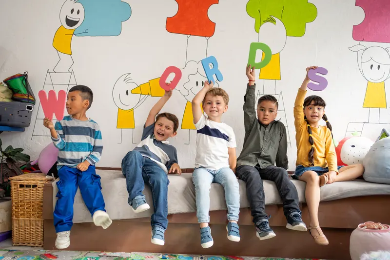Fünf Kinder halten bunte Buchstaben hoch und lachen – Freude am Lernen in der Praxis für kindliche Entwicklung in Steyr